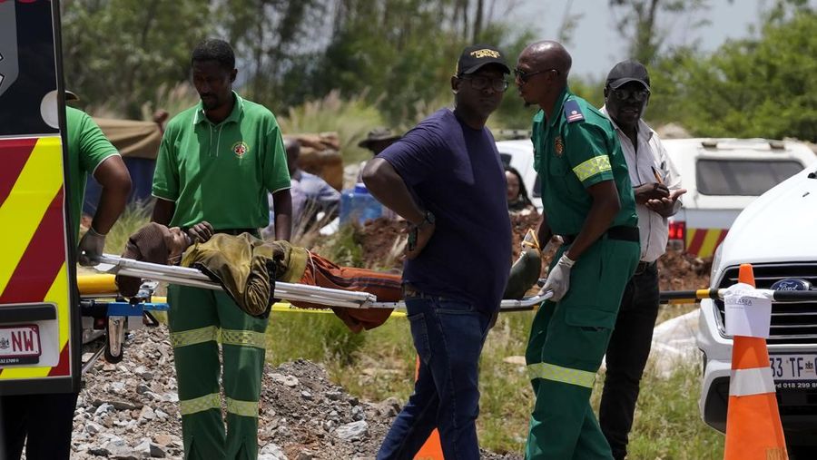 Petugas forensik membawa jenazah dalam kantong jenazah biru selama operasi penyelamatan para penambang dari bawah tanah di tambang emas terbengkalai di Stilfontein, Afrika Selatan, Selasa, 14 Januari 2025. (AP Photo/Themba Hadebe)