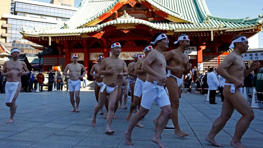 Para peserta menyiram diri mereka dengan air dingin selama upacara tahunan ketahanan air dingin untuk memurnikan jiwa mereka dan mengharapkan keberuntungan di tahun baru, di kuil Kanda Myojin di Tokyo, Jepang, 18 Januari 2025. (REUTERS/Issei Kato)