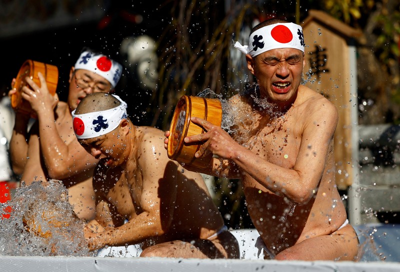 Para peserta menyiram diri mereka dengan air dingin selama upacara tahunan ketahanan air dingin untuk memurnikan jiwa mereka dan mengharapkan keberuntungan di tahun baru, di kuil Kanda Myojin di Tokyo, Jepang, 18 Januari 2025. (REUTERS/Issei Kato)