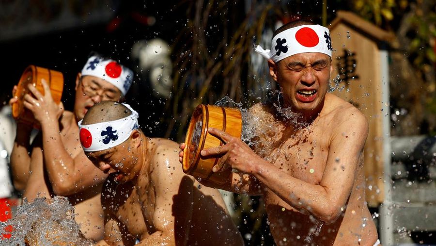 Para peserta menyiram diri mereka dengan air dingin selama upacara tahunan ketahanan air dingin untuk memurnikan jiwa mereka dan mengharapkan keberuntungan di tahun baru, di kuil Kanda Myojin di Tokyo, Jepang, 18 Januari 2025. (REUTERS/Issei Kato)