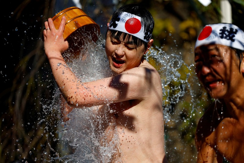 Para peserta menyiram diri mereka dengan air dingin selama upacara tahunan ketahanan air dingin untuk memurnikan jiwa mereka dan mengharapkan keberuntungan di tahun baru, di kuil Kanda Myojin di Tokyo, Jepang, 18 Januari 2025. (REUTERS/Issei Kato)