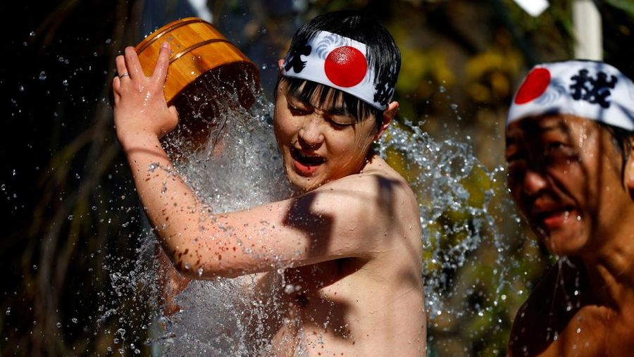 Para peserta menyiram diri mereka dengan air dingin selama upacara tahunan ketahanan air dingin untuk memurnikan jiwa mereka dan mengharapkan keberuntungan di tahun baru, di kuil Kanda Myojin di Tokyo, Jepang, 18 Januari 2025. (REUTERS/Issei Kato)
