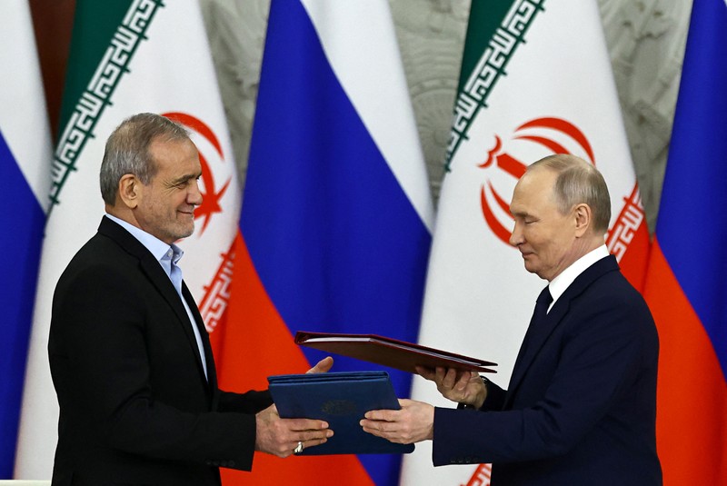 Presiden Rusia Vladimir Putin dan Presiden Iran Masoud Pezeshkian berjabat tangan saat bertemu di Moskow, Rusia, 17 Januari 2025. (REUTERS/Evgenia Novozhenina/Pool)