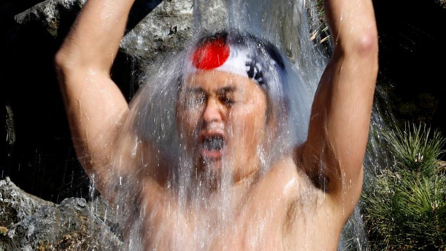 Para peserta menyiram diri mereka dengan air dingin selama upacara tahunan ketahanan air dingin untuk memurnikan jiwa mereka dan mengharapkan keberuntungan di tahun baru, di kuil Kanda Myojin di Tokyo, Jepang, 18 Januari 2025. (REUTERS/Issei Kato)