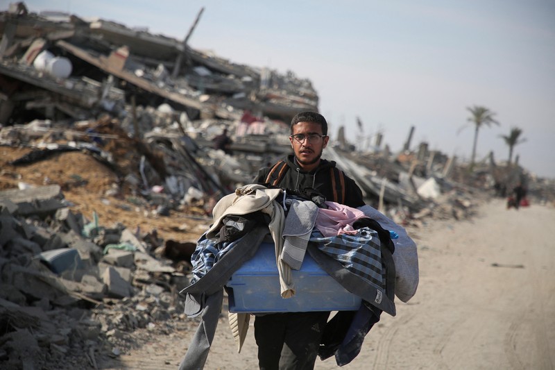 Warga Palestina yang mengungsi berjalan melewati puing-puing saat mencoba kembali ke rumah mereka menyusul penundaan gencatan senjata antara Israel dan Hamas mengenai daftar sandera, di Jalur Gaza utara 19 Januari 2025. Warga Palestina yang mengungsi berjalan melewati puing-puing saat mencoba kembali ke rumah mereka menyusul penundaan gencatan senjata antara Israel dan Hamas mengenai daftar sandera, di Jalur Gaza utara 19 Januari 2025. (REUTERS/Khalil Ramzi)