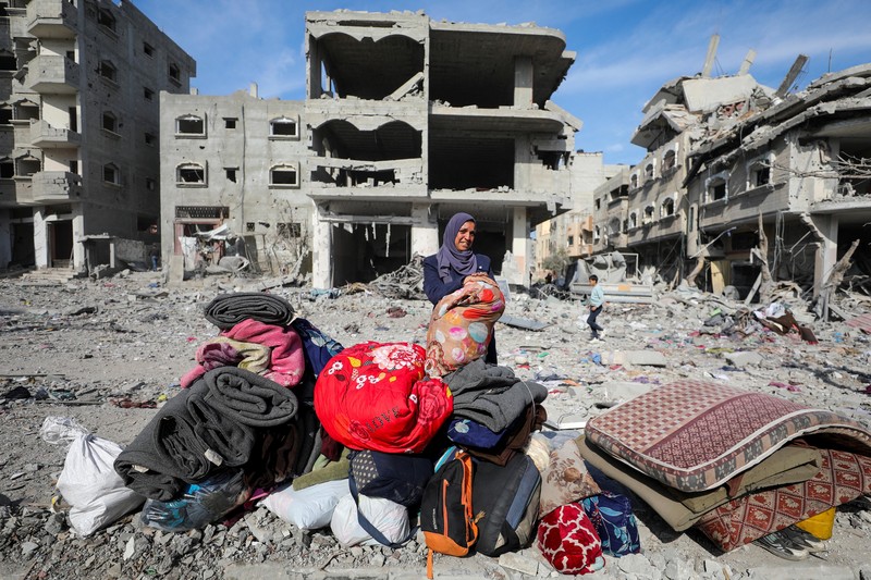 Warga Palestina yang mengungsi berjalan melewati puing-puing saat mencoba kembali ke rumah mereka menyusul penundaan gencatan senjata antara Israel dan Hamas mengenai daftar sandera, di Jalur Gaza utara 19 Januari 2025. (REUTERS/Khalil Ramzi)