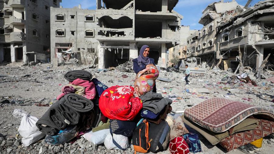 Warga Palestina yang mengungsi berjalan melewati puing-puing saat mencoba kembali ke rumah mereka menyusul penundaan gencatan senjata antara Israel dan Hamas mengenai daftar sandera, di Jalur Gaza utara 19 Januari 2025. (REUTERS/Khalil Ramzi)