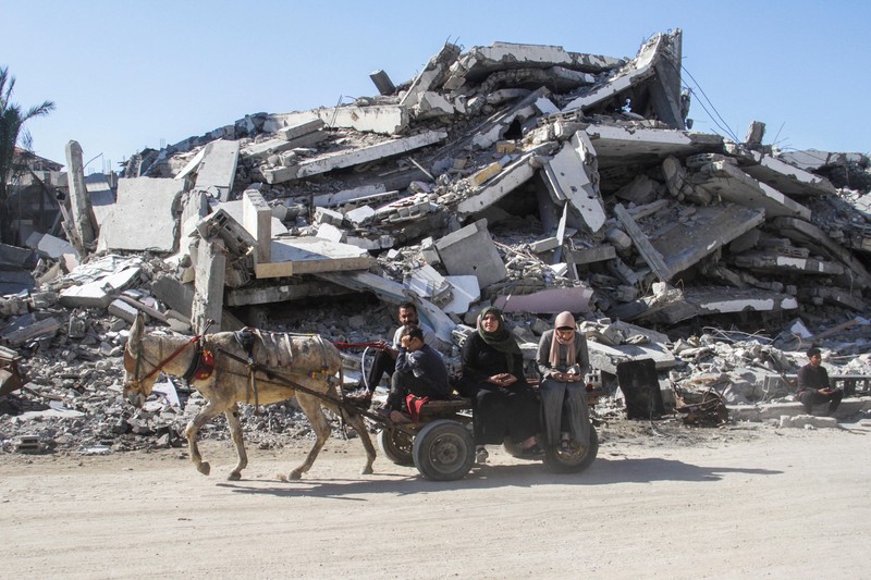 Warga Palestina yang mengungsi berjalan melewati puing-puing saat mencoba kembali ke rumah mereka menyusul penundaan gencatan senjata antara Israel dan Hamas mengenai daftar sandera, di Jalur Gaza utara 19 Januari 2025. (REUTERS/Khalil Ramzi)