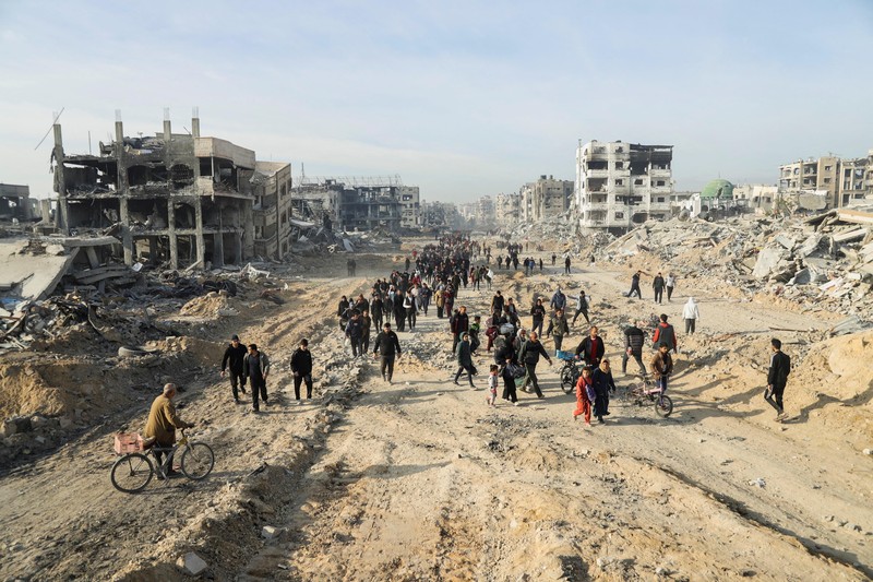 Warga Palestina yang mengungsi berjalan melewati puing-puing saat mencoba kembali ke rumah mereka menyusul penundaan gencatan senjata antara Israel dan Hamas mengenai daftar sandera, di Jalur Gaza utara 19 Januari 2025. Warga Palestina yang mengungsi berjalan melewati puing-puing saat mencoba kembali ke rumah mereka menyusul penundaan gencatan senjata antara Israel dan Hamas mengenai daftar sandera, di Jalur Gaza utara 19 Januari 2025. (REUTERS/Khalil Ramzi)