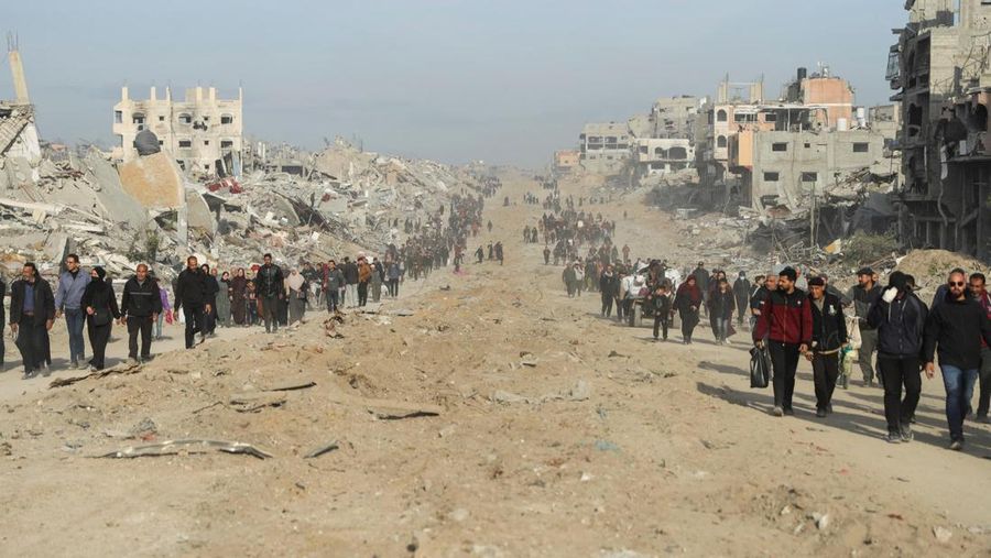 Warga Palestina yang mengungsi berjalan melewati puing-puing saat mencoba kembali ke rumah mereka menyusul penundaan gencatan senjata antara Israel dan Hamas mengenai daftar sandera, di Jalur Gaza utara 19 Januari 2025. (REUTERS/Khalil Ramzi)
