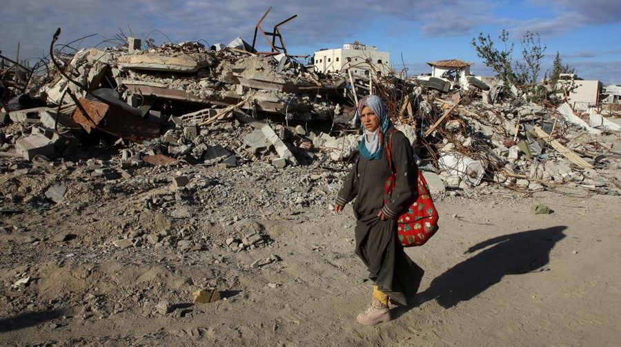 A Palestinian woman walks past the rubble of houses and buildings destroyed during the war, following a ceasefire between Israel and Hamas, in Rafah in the southern Gaza Strip, January 20, 2025. REUTERS/Hatem Khaled