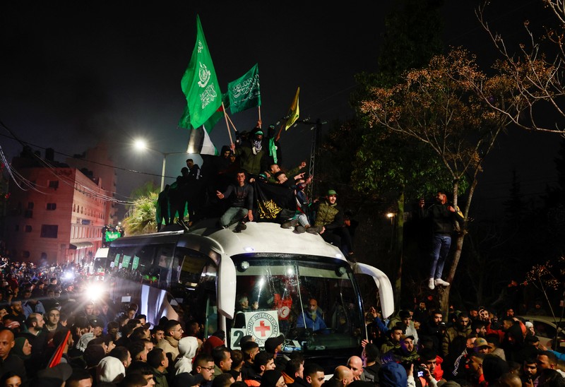 Orang-orang yang membawa bendera berdiri di atas bus saat mereka bereaksi terhadap kedatangan bus yang membawa warga Palestina yang dibebaskan dari penjara Israel sebagai bagian dari pertukaran sandera-tahanan dan kesepakatan gencatan senjata antara Hamas dan Israel, di Ramallah di Tepi Barat yang diduduki Israel. 20 Januari 2025. Orang-orang yang membawa bendera berdiri di atas bus saat mereka bereaksi terhadap kedatangan bus yang membawa warga Palestina yang dibebaskan dari penjara Israel sebagai bagian dari pertukaran sandera-tahanan dan kesepakatan gencatan senjata antara Hamas dan Israel, di Ramallah di Tepi Barat yang diduduki Israel. 20 Januari 2025. (REUTERS/Mussa Qawasma)