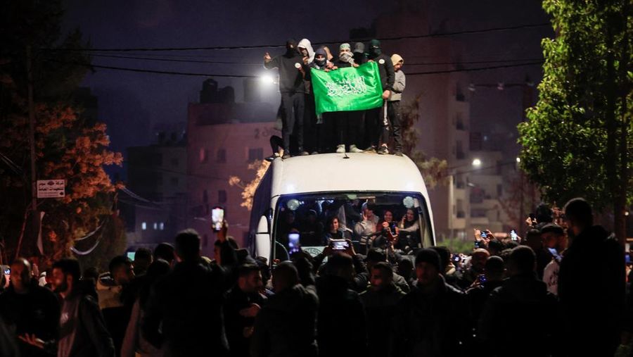 Orang-orang yang membawa bendera berdiri di atas bus saat mereka bereaksi terhadap kedatangan bus yang membawa warga Palestina yang dibebaskan dari penjara Israel sebagai bagian dari pertukaran sandera-tahanan dan kesepakatan gencatan senjata antara Hamas dan Israel, di Ramallah di Tepi Barat yang diduduki Israel. 20 Januari 2025. (REUTERS/Mussa Qawasma)