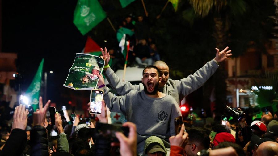 Orang-orang yang membawa bendera berdiri di atas bus saat mereka bereaksi terhadap kedatangan bus yang membawa warga Palestina yang dibebaskan dari penjara Israel sebagai bagian dari pertukaran sandera-tahanan dan kesepakatan gencatan senjata antara Hamas dan Israel, di Ramallah di Tepi Barat yang diduduki Israel. 20 Januari 2025. (REUTERS/Mussa Qawasma)