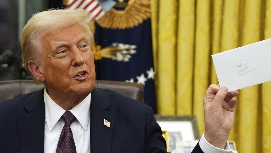 President Donald Trump holds a letter that former President Joe Biden left for him as signs executive orders in the Oval Office of the White House, Monday, Jan. 20, 2025, in Washington. (AP Photo/Evan Vucci)