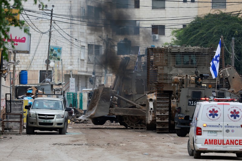 Israel Palestinians Israeli military vehicles guard a road where a military bulldozer operates in the West Bank refugee camp of Jenin Wednesday, Jan. 22, 2025. (AP Photo/Majdi Mohammed)