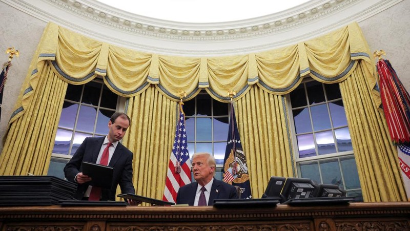 Presiden AS Donald Trump menandatangani dokumen saat mengeluarkan perintah eksekutif dan pengampunan bagi para terdakwa 6 Januari di Ruang Oval di Gedung Putih pada Hari Pelantikan di Washington, AS, 20 Januari 2025. (REUTERS/Carlos Barria)