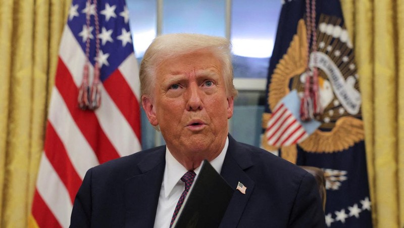 Presiden AS Donald Trump menandatangani dokumen saat mengeluarkan perintah eksekutif dan pengampunan bagi para terdakwa 6 Januari di Ruang Oval di Gedung Putih pada Hari Pelantikan di Washington, AS, 20 Januari 2025. (REUTERS/Carlos Barria)