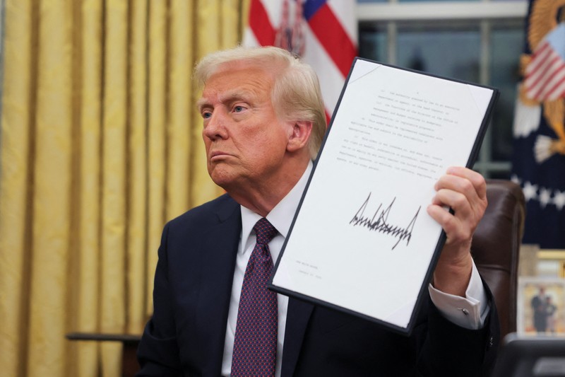 Presiden AS Donald Trump menandatangani dokumen saat mengeluarkan perintah eksekutif dan pengampunan bagi para terdakwa 6 Januari di Ruang Oval di Gedung Putih pada Hari Pelantikan di Washington, AS, 20 Januari 2025. (REUTERS/Carlos Barria)