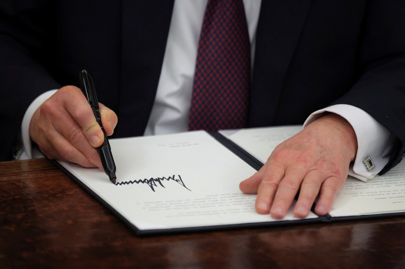 Presiden AS Donald Trump menandatangani dokumen saat mengeluarkan perintah eksekutif dan pengampunan bagi para terdakwa 6 Januari di Ruang Oval di Gedung Putih pada Hari Pelantikan di Washington, AS, 20 Januari 2025. (REUTERS/Carlos Barria)