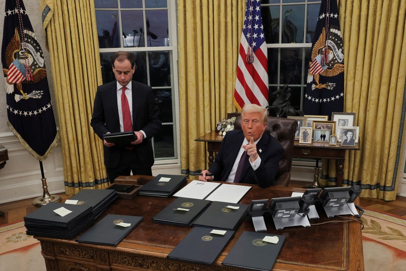 Presiden AS Donald Trump menandatangani dokumen saat mengeluarkan perintah eksekutif dan pengampunan bagi para terdakwa 6 Januari di Ruang Oval di Gedung Putih pada Hari Pelantikan di Washington, AS, 20 Januari 2025. (REUTERS/Carlos Barria)