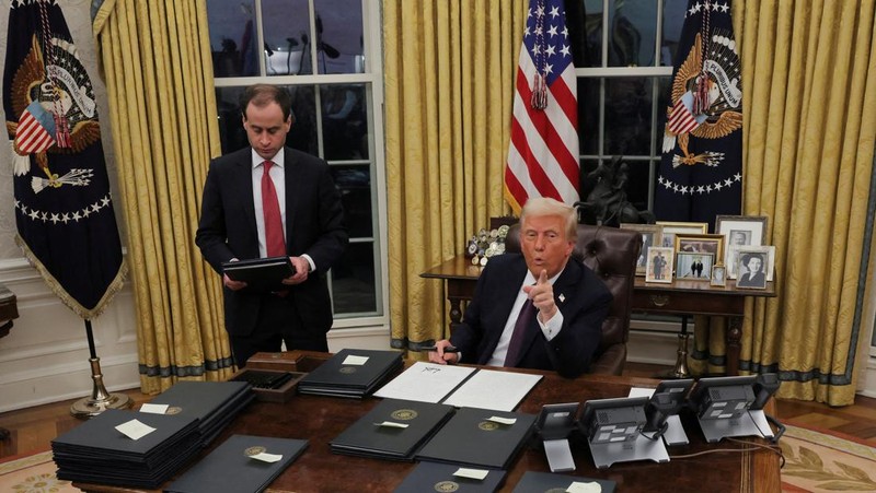 Presiden AS Donald Trump menandatangani dokumen saat mengeluarkan perintah eksekutif dan pengampunan bagi para terdakwa 6 Januari di Ruang Oval di Gedung Putih pada Hari Pelantikan di Washington, AS, 20 Januari 2025. (REUTERS/Carlos Barria)