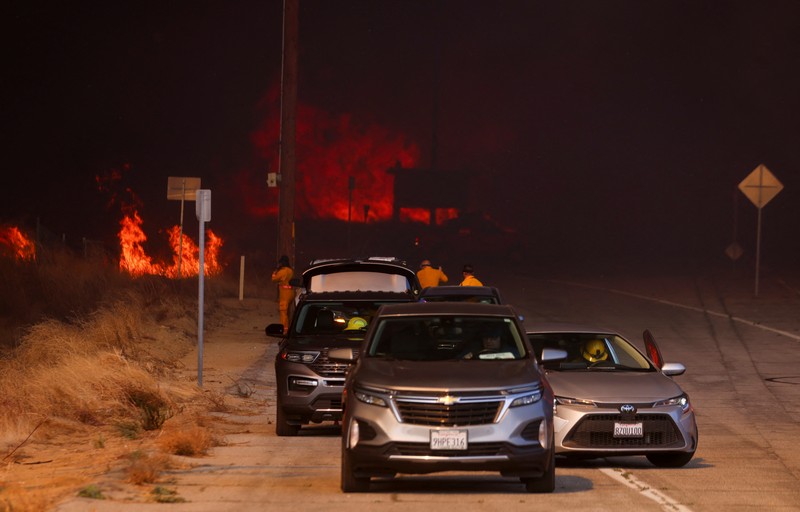 Anggota media bekerja saat asap dan api mengepul saat petugas pemadam kebakaran berjuang memadamkan Kebakaran Hughes di dekat Danau Castaic, utara Santa Clarita, California, AS, 22 Januari 2025. Anggota media bekerja saat asap dan api mengepul saat petugas pemadam kebakaran berjuang memadamkan Kebakaran Hughes di dekat Danau Castaic, utara Santa Clarita, California, AS, 22 Januari 2025. (REUTERS/David Swanson)