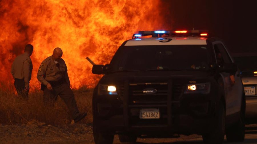 Anggota media bekerja saat asap dan api mengepul saat petugas pemadam kebakaran berjuang memadamkan Kebakaran Hughes di dekat Danau Castaic, utara Santa Clarita, California, AS, 22 Januari 2025. (REUTERS/David Swanson)