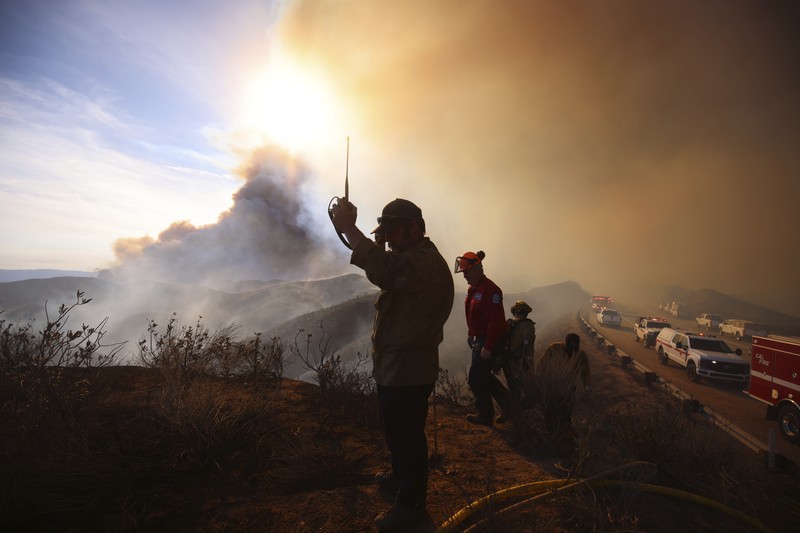 Anggota media bekerja saat asap dan api mengepul saat petugas pemadam kebakaran berjuang memadamkan Kebakaran Hughes di dekat Danau Castaic, utara Santa Clarita, California, AS, 22 Januari 2025. Anggota media bekerja saat asap dan api mengepul saat petugas pemadam kebakaran berjuang memadamkan Kebakaran Hughes di dekat Danau Castaic, utara Santa Clarita, California, AS, 22 Januari 2025. (REUTERS/David Swanson)