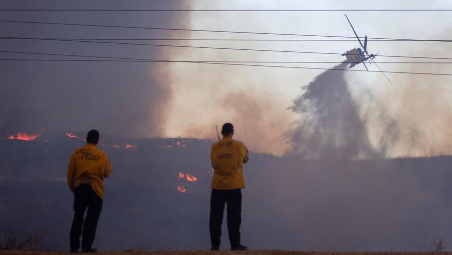 Seorang petugas pemadam kebakaran membawa obor tetes saat ia menyalakan api unggun untuk memadamkan Kebakaran Hughes yang membakar sepanjang lereng bukit di Castaic, California, Rabu, 22 Januari 2025. (AP Photo/Jae C. Hong)