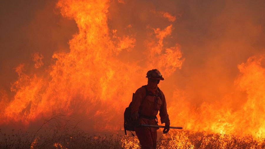 Seorang petugas pemadam kebakaran membawa obor tetes saat ia menyalakan api unggun untuk memadamkan Kebakaran Hughes yang membakar sepanjang lereng bukit di Castaic, California, Rabu, 22 Januari 2025. (AP Photo/Jae C. Hong)