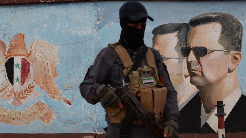 Seorang anggota bekas kelompok pemberontak Hayat Tahrir al-Sham berjaga di dekat tumpukan obat-obatan terlarang yang terbakar, di bawah pengawasan Departemen Pengendalian Narkotika di Kementerian Dalam Negeri Suriah, di Damaskus, Suriah, 23 Januari 2025. (REUTERS/Yamam Al Shaar)