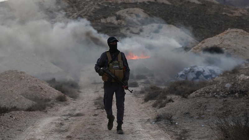 Seorang anggota bekas kelompok pemberontak Hayat Tahrir al-Sham berjaga di dekat tumpukan obat-obatan terlarang yang terbakar, di bawah pengawasan Departemen Pengendalian Narkotika di Kementerian Dalam Negeri Suriah, di Damaskus, Suriah, 23 Januari 2025. (REUTERS/Yamam Al Shaar)