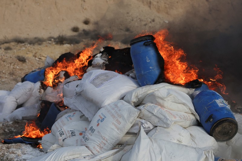 Seorang anggota bekas kelompok pemberontak Hayat Tahrir al-Sham berjaga di dekat tumpukan obat-obatan terlarang yang terbakar, di bawah pengawasan Departemen Pengendalian Narkotika di Kementerian Dalam Negeri Suriah, di Damaskus, Suriah, 23 Januari 2025. Seorang anggota bekas kelompok pemberontak Hayat Tahrir al-Sham berjaga di dekat tumpukan obat-obatan terlarang yang terbakar, di bawah pengawasan Departemen Pengendalian Narkotika di Kementerian Dalam Negeri Suriah, di Damaskus, Suriah, 23 Januari 2025. (REUTERS/Yamam Al Shaar)