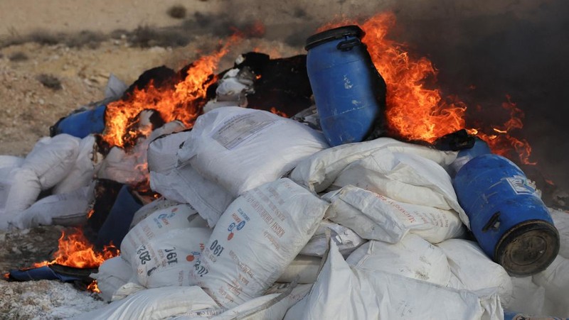 Seorang anggota bekas kelompok pemberontak Hayat Tahrir al-Sham berjaga di dekat tumpukan obat-obatan terlarang yang terbakar, di bawah pengawasan Departemen Pengendalian Narkotika di Kementerian Dalam Negeri Suriah, di Damaskus, Suriah, 23 Januari 2025. (REUTERS/Yamam Al Shaar)