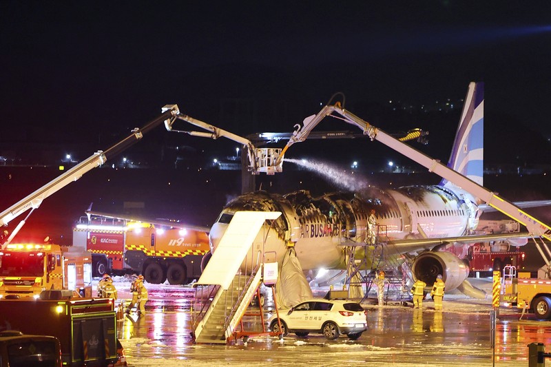 Petugas pemadam kebakaran berupaya memadamkan api pada pesawat Air Busan di Bandara Internasional Gimhae di Busan, Korea Selatan, Selasa (28/1/2025). (Son Hyung-joo/Yonhap via AP) Petugas pemadam kebakaran berupaya memadamkan api pada pesawat Air Busan di Bandara Internasional Gimhae di Busan, Korea Selatan, Selasa (28/1/2025). (Son Hyung-joo/Yonhap via AP)