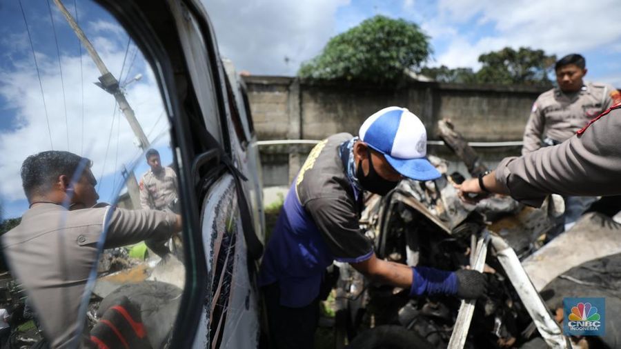 Petugas memeriksa bangkai kendaraan yang terbakar dalam kecelakaan di Gerbang Tol Ciawi kini berada di Kantor PJR Ciawi, Rabu (5/2/2025). (CNBC Indonesia/Tri Susilo)