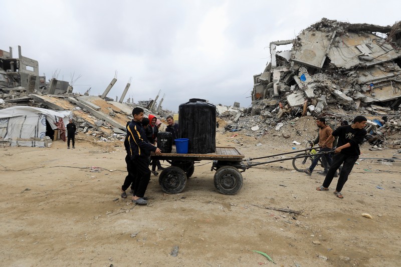 Seorang warga Palestina membawa air di tengah gencatan senjata antara Israel dan Hamas, di kamp pengungsi Jabalia di Jalur Gaza utara, 4 Februari 2025. (REUTERS/Mahmoud Issa)