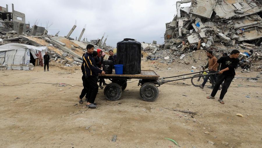 Warga Palestina mendorong gerobak berisi tangki air di tengah gencatan senjata antara Israel dan Hamas, di kamp pengungsi Jabalia di Jalur Gaza utara, 5 Februari 2025. (REUTERS/Mahmoud Issa)