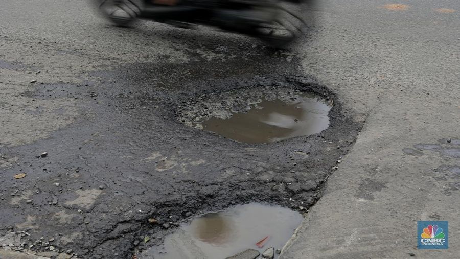 Pengendara melewati jalan rusak berlubang di Jalan Raya Parung-Ciputat, Bojongsari, Kota Depok, Jawa Barat, Jumat (7/1/2025). (CNBC Indonesia/Muhammad Sabki)