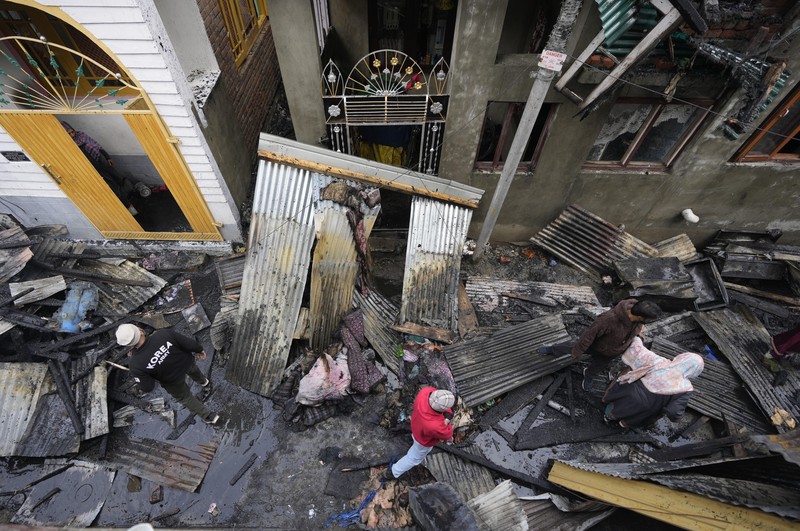 Seorang anak laki-laki Kashmir berjalan di atas puing-puing rumah yang rusak setelah kebakaran di rumah-rumah penduduk di Srinagar, Kashmir yang dikuasai India, Senin, 10 Februari 2025. (AP Photo/Mukhtar Khan)