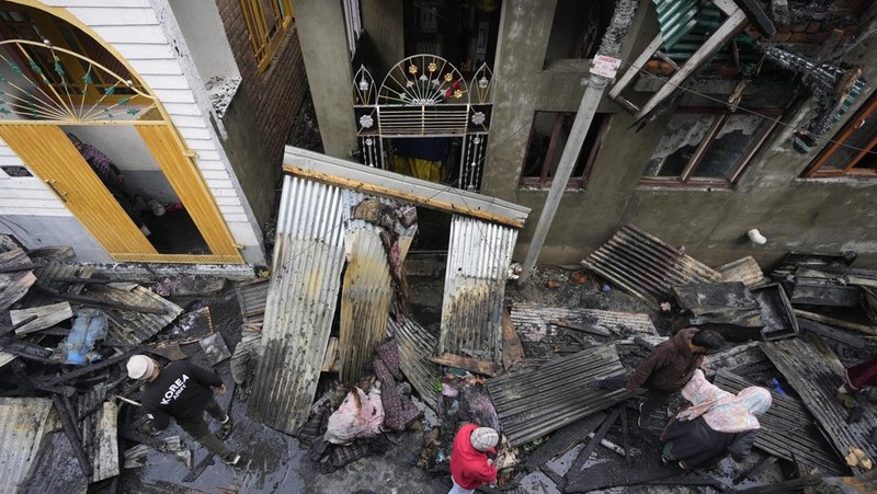 Seorang anak laki-laki Kashmir berjalan di atas puing-puing rumah yang rusak setelah kebakaran di rumah-rumah penduduk di Srinagar, Kashmir yang dikuasai India, Senin, 10 Februari 2025. (AP Photo/Mukhtar Khan)