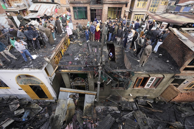 Seorang anak laki-laki Kashmir berjalan di atas puing-puing rumah yang rusak setelah kebakaran di rumah-rumah penduduk di Srinagar, Kashmir yang dikuasai India, Senin, 10 Februari 2025. (AP Photo/Mukhtar Khan)