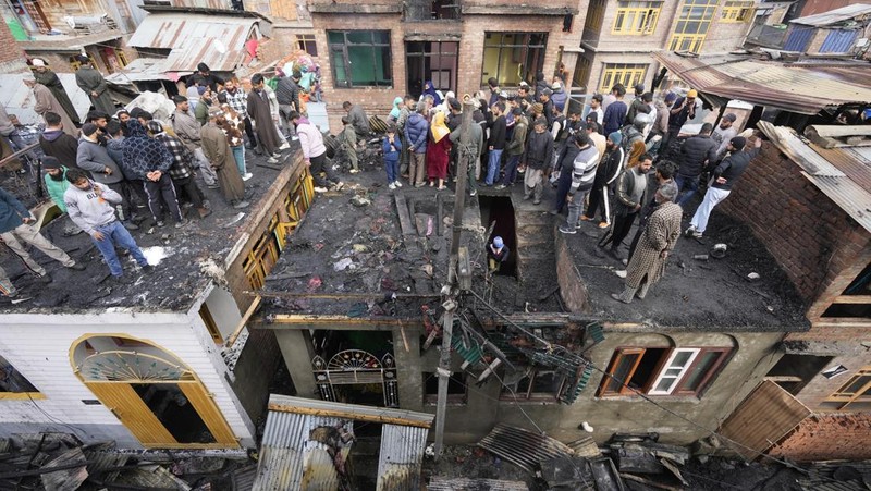 Seorang anak laki-laki Kashmir berjalan di atas puing-puing rumah yang rusak setelah kebakaran di rumah-rumah penduduk di Srinagar, Kashmir yang dikuasai India, Senin, 10 Februari 2025. (AP Photo/Mukhtar Khan)