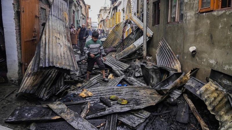 Seorang anak laki-laki Kashmir berjalan di atas puing-puing rumah yang rusak setelah kebakaran di rumah-rumah penduduk di Srinagar, Kashmir yang dikuasai India, Senin, 10 Februari 2025. (AP Photo/Mukhtar Khan)
