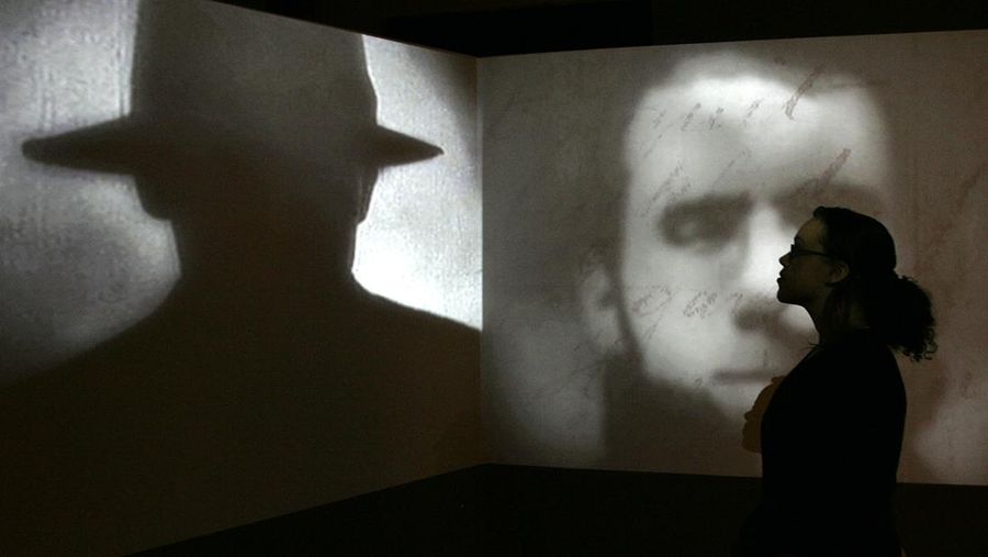 Seorang anggota staf berpose di depan layar yang menayangkan film pendek tentang Jack the Ripper selama pameran