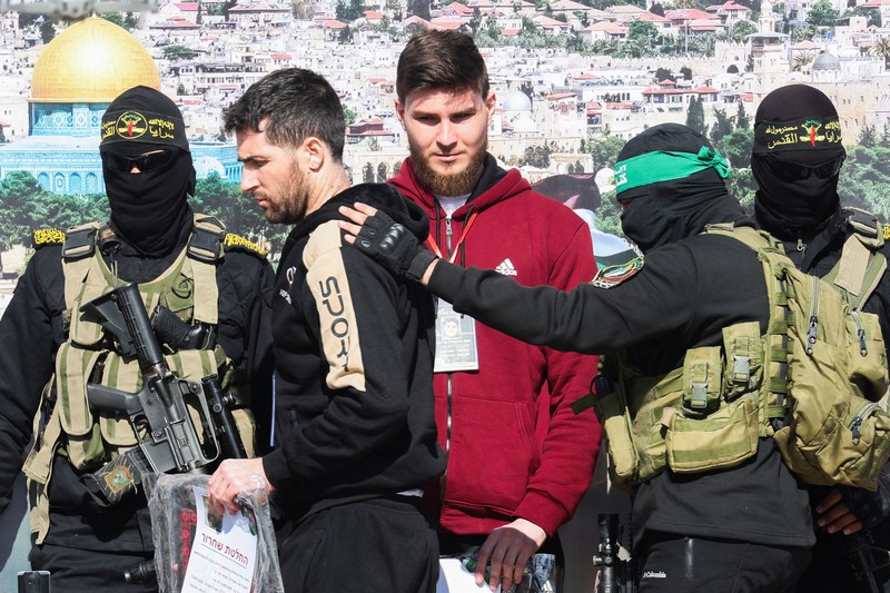 ISRAEL-PALESTINIANS/GAZA-CEASEFIRE A drone view shows Palestinian Hamas and Islamic Jihad militants escorting Iair Horn, U.S.-Israeli Sagui Dekel-Chen and Russian-Israeli Sasha (Alexander) Troufanov, hostages held in Gaza since the deadly October 7, 2023 attack, as they released as part of a ceasefire and a hostages-prisoners swap deal between Hamas and Israel in Khan Younis, in the southern Gaza Strip, February 15, 2025. REUTERS/Stringer