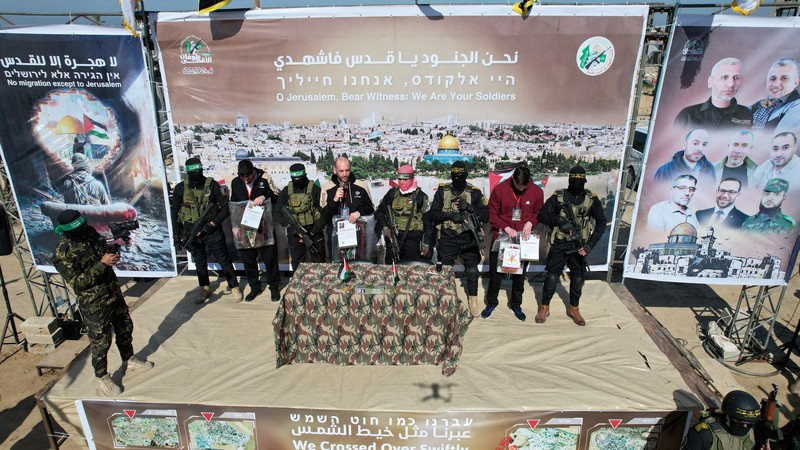 A drone view shows Palestinian Hamas and Islamic Jihad militants escorting Iair Horn, U.S.-Israeli Sagui Dekel-Chen and Russian-Israeli Sasha (Alexander) Troufanov, hostages held in Gaza since the deadly October 7, 2023 attack, as they released as part of a ceasefire and a hostages-prisoners swap deal between Hamas and Israel in Khan Younis, in the southern Gaza Strip, February 15, 2025. REUTERS/Stringer