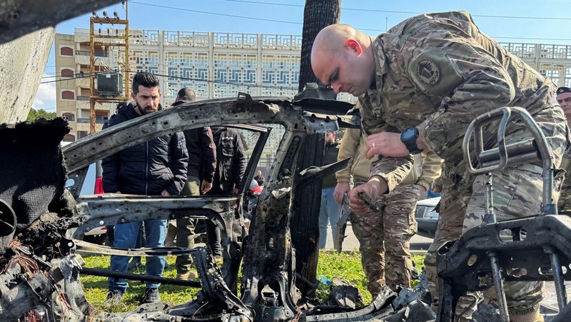 Warga dan pasukan keamanan berkumpul di dekat mobil yang rusak setelah serangan Israel, menurut sumber keamanan, di kota pelabuhan selatan Sidon, Lebanon, 17 Februari 2025. (REUTERS/ALI HANKIR)