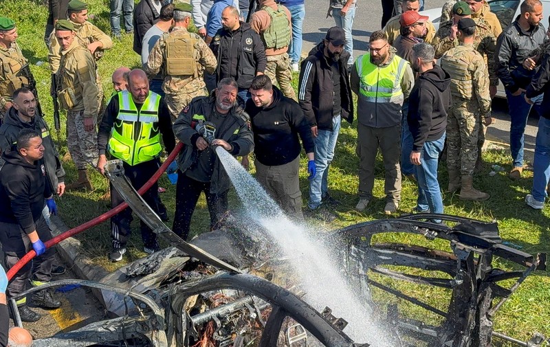 Warga dan pasukan keamanan berkumpul di dekat mobil yang rusak setelah serangan Israel, menurut sumber keamanan, di kota pelabuhan selatan Sidon, Lebanon, 17 Februari 2025. (REUTERS/ALI HANKIR)
